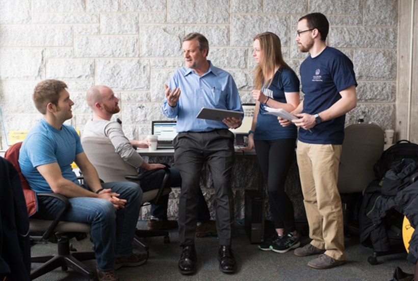 RISE Forum Director Karl Schmidt stands and talks with students in a classroom.
