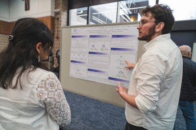Graduate student explains the research displayed on a poster