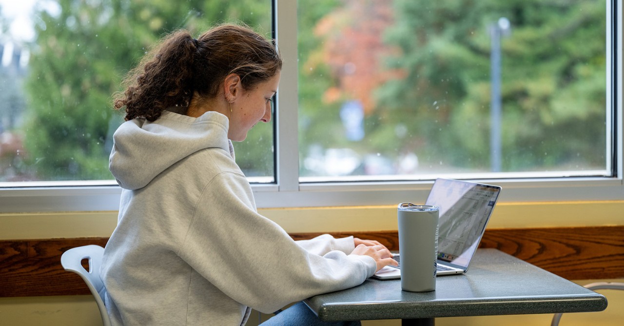 Student working on laptop sitting at a table