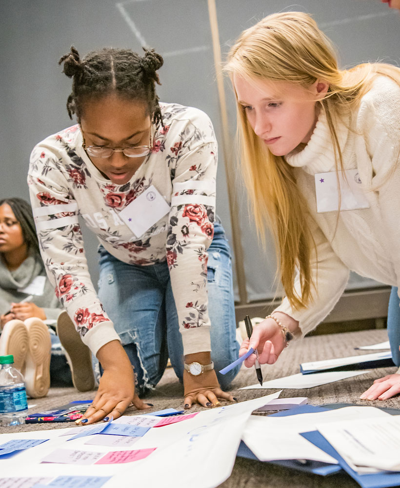 Two female students kneeling on floor working on project