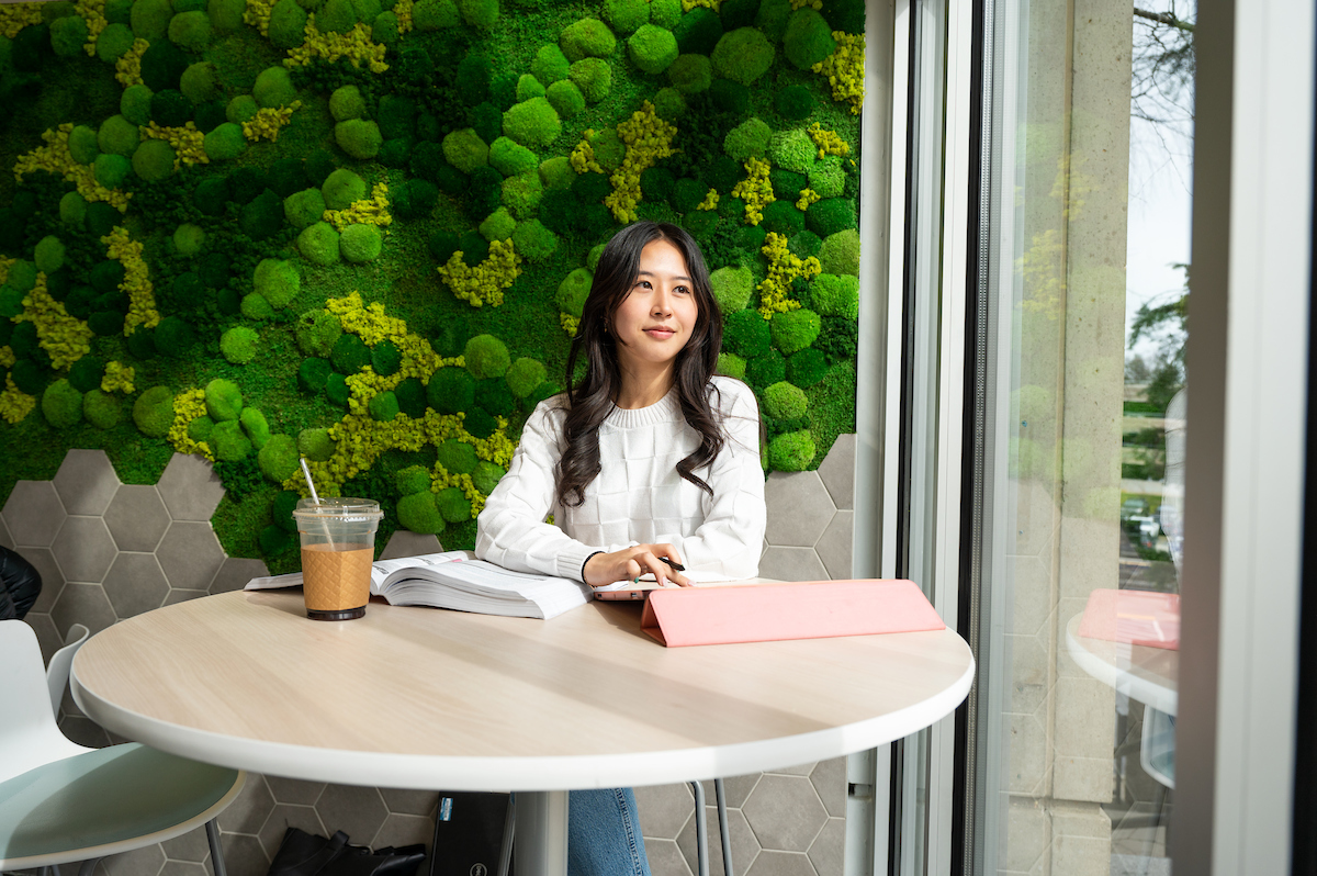 woman working on a tablet in a coffee shop looking out the window