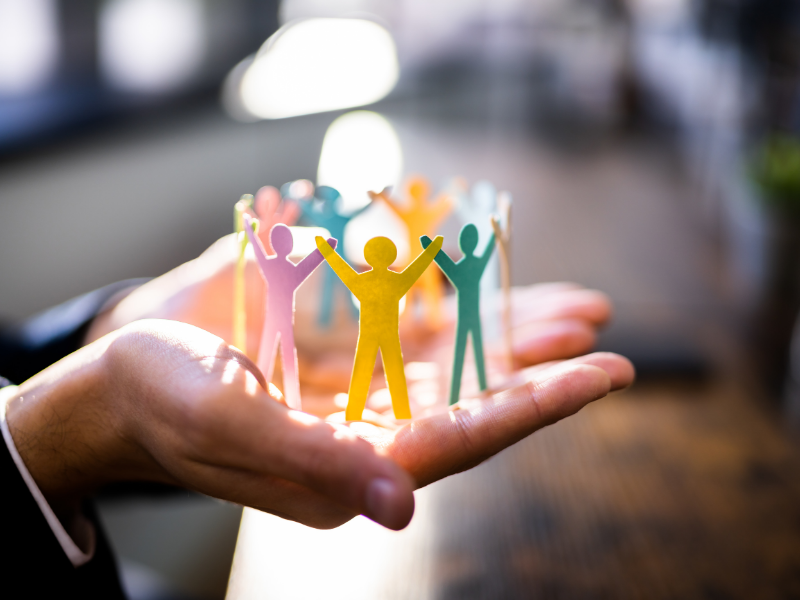 photo of open hands holding people paper cut outs